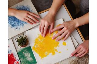 Mani che creano un oggetto con argilla o vernice, colori vivaci e un senso di manualità.